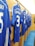 A row of blue football jerseys hangs on wooden lockers, each bearing names and numbers on the back. The setting appears to be a team's changing room with a polished, organized look.