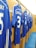 A row of blue football jerseys hangs on wooden lockers, each bearing names and numbers on the back. The setting appears to be a team's changing room with a polished, organized look.