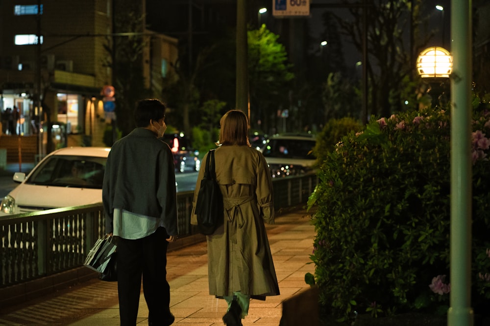 a man and woman walking down a sidewalk at night