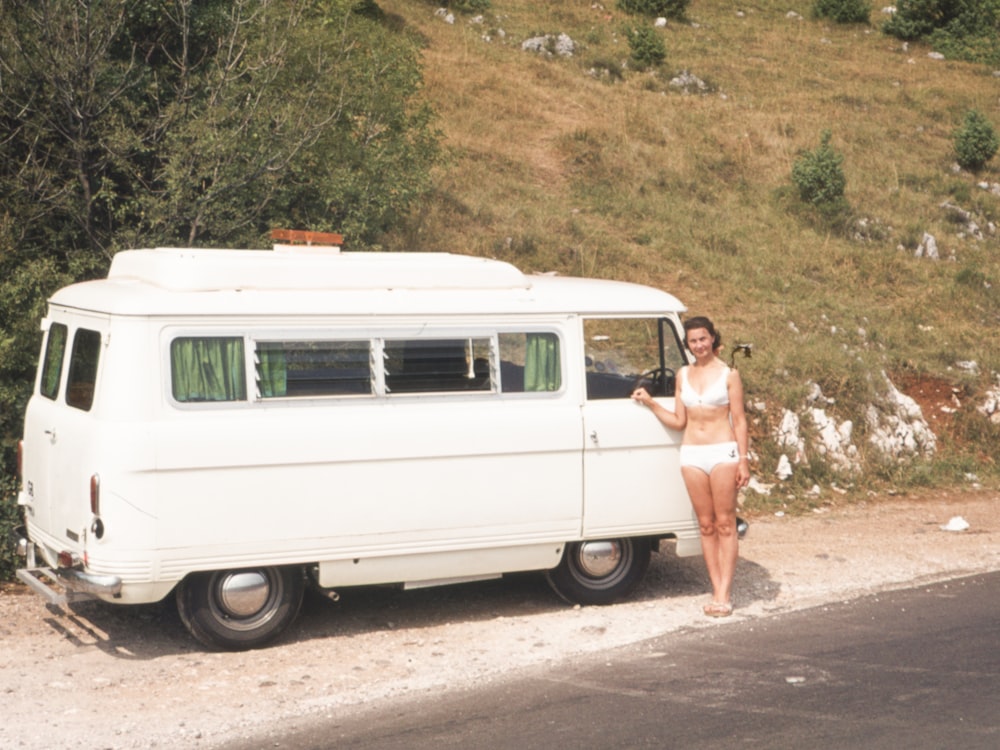 a woman standing next to a white van on the side of a road