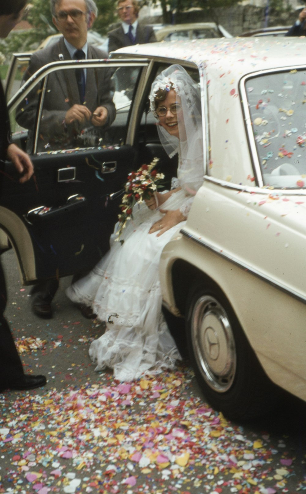 a bride and groom getting out of a car