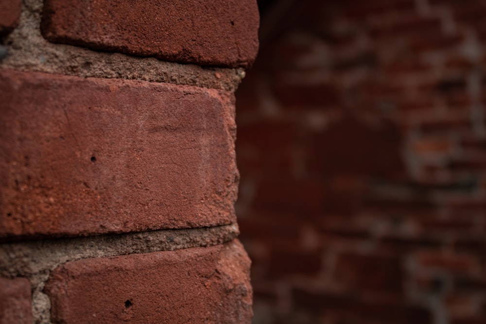 a close up of a brick wall with a red brick building in the background