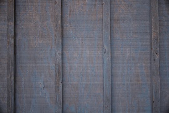 Panels of wooden siding with a weathered, aged appearance. The surface has visible grain and a slightly rough texture.