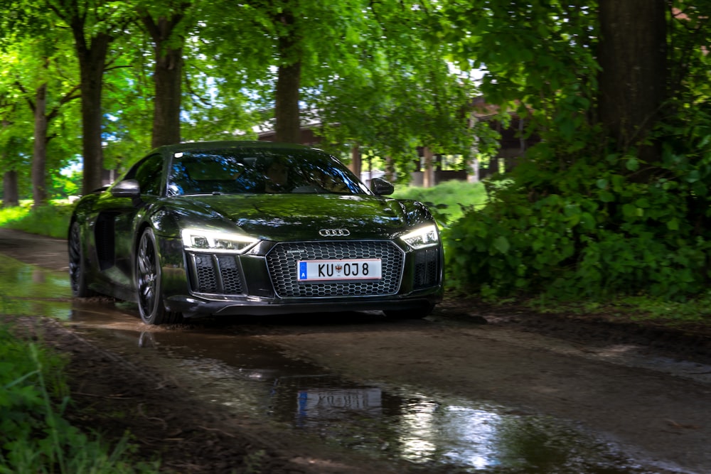 a black car driving down a wet road