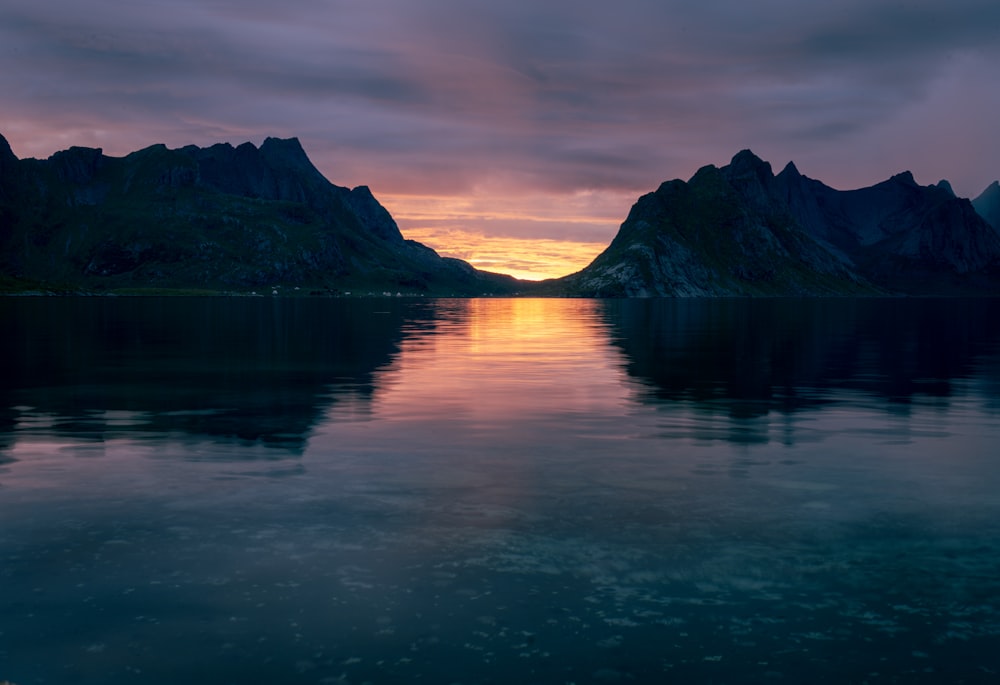 a lake with mountains in the background at sunset