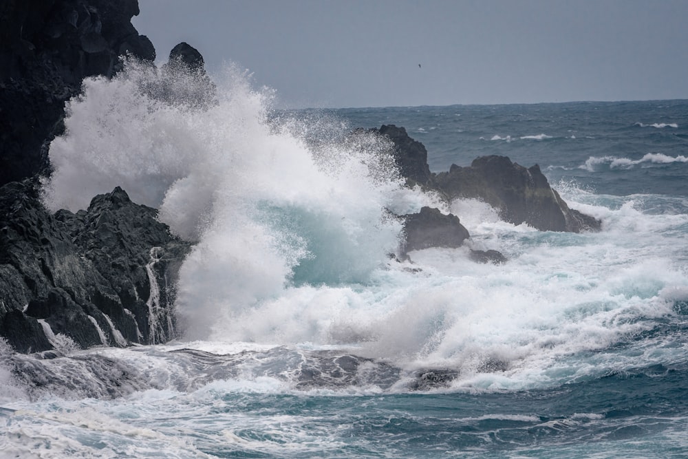 a large wave crashing into a rocky shore
