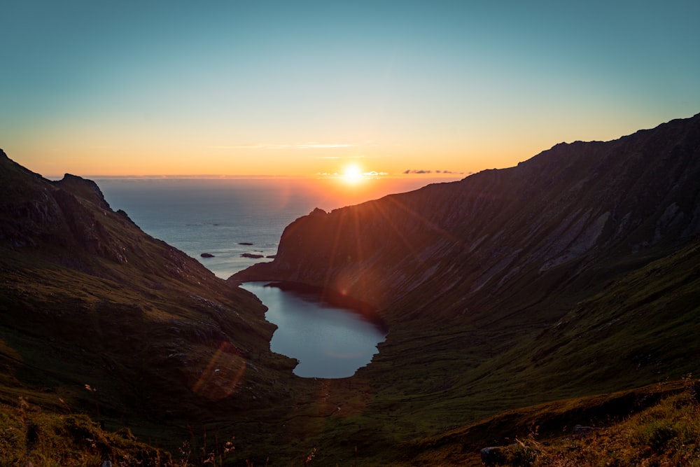 the sun is setting over a lake in the mountains