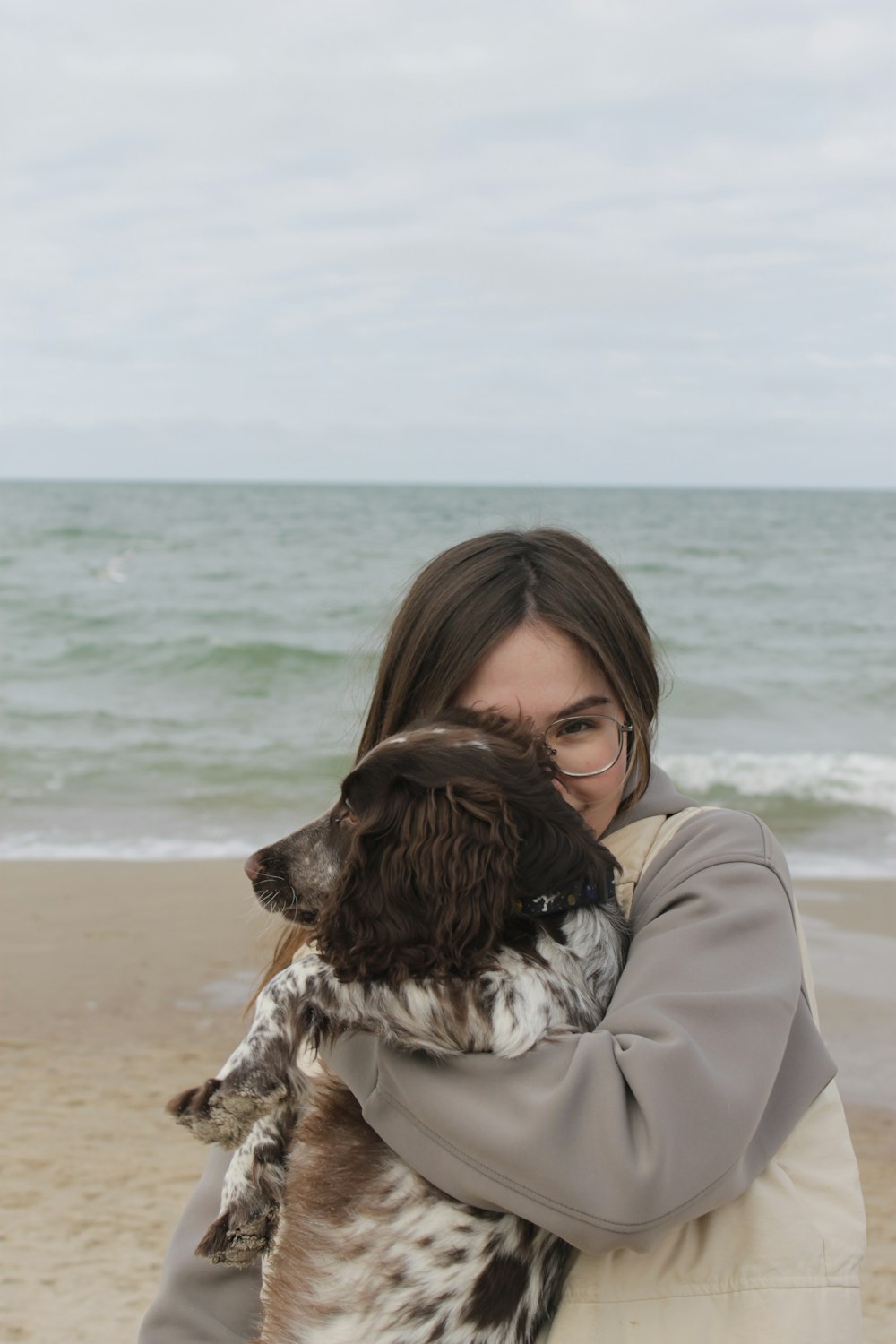 a woman holding a dog on the beach