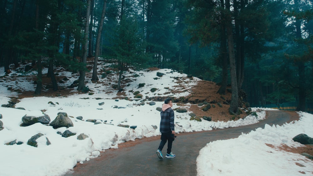 Una persona in piedi su un sentiero innevato nel bosco