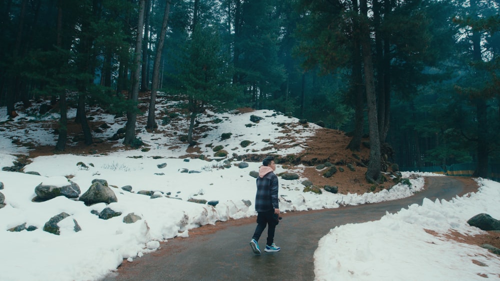 a person standing on a snowy path in the woods