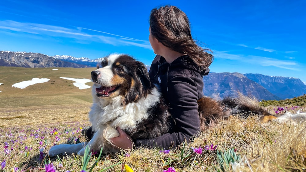 a woman sitting in a field with a dog