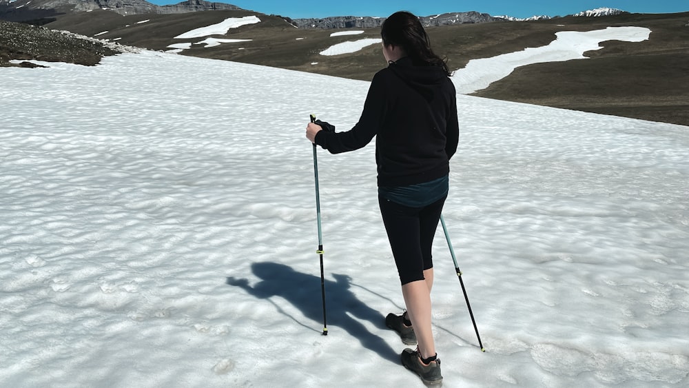 uma mulher nos esquis está de pé na neve