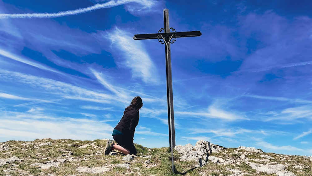 a person kneeling down in front of a cross