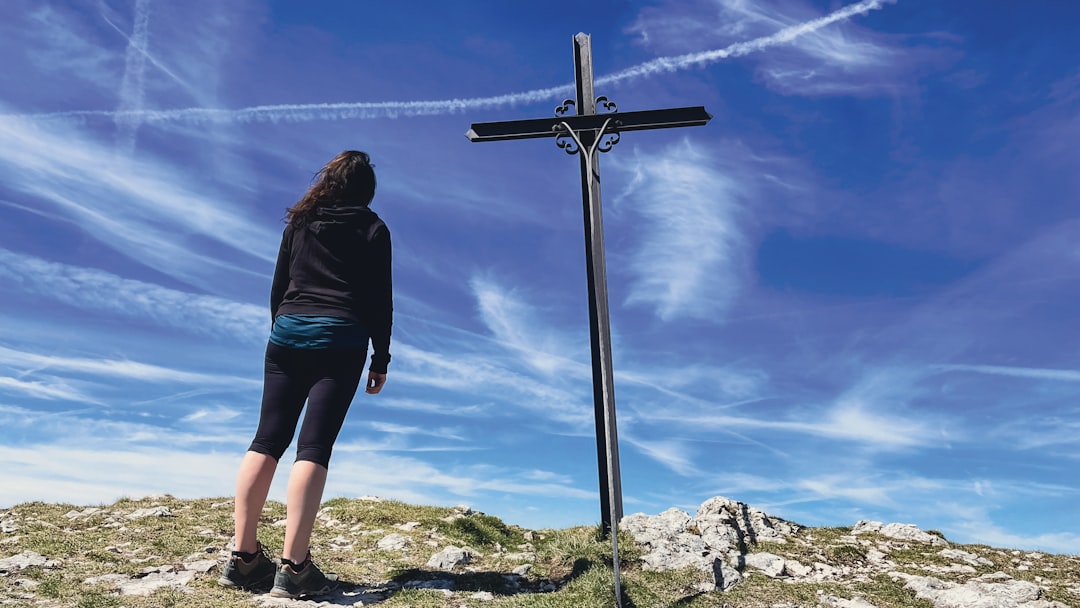 a woman standing next to a cross on top of a hill,