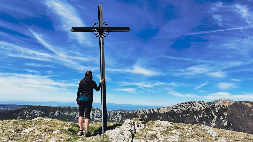 a woman standing at the top of a mountain holding a cross