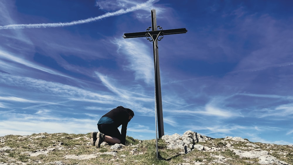 a person kneeling down next to a cross