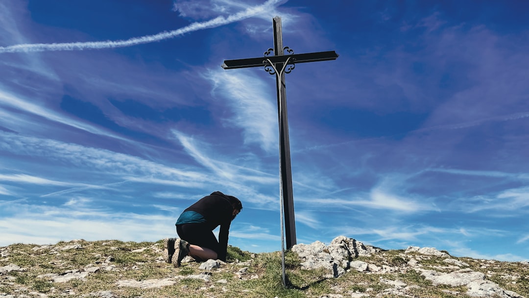 a person kneeling down next to a cross