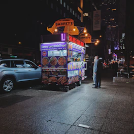 a man standing in front of a food cart