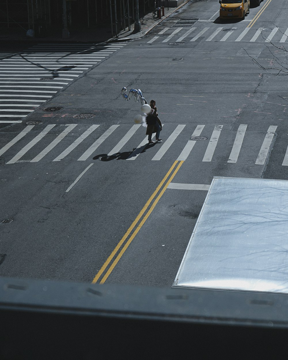 a person walking across a street holding a kite