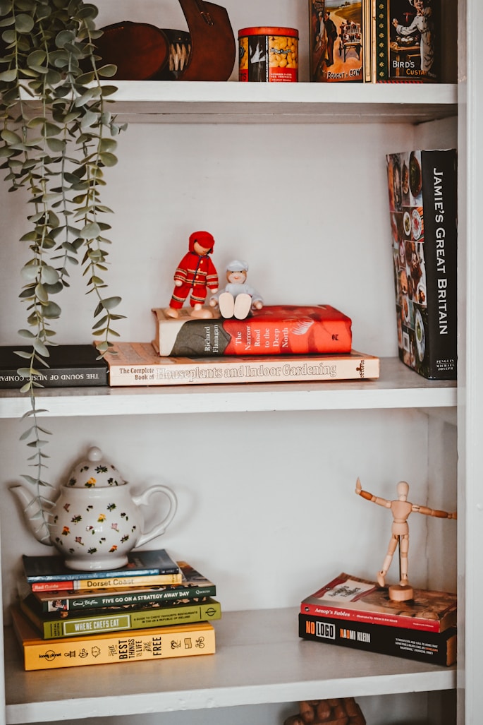 a white book shelf with books and a red teddy bear