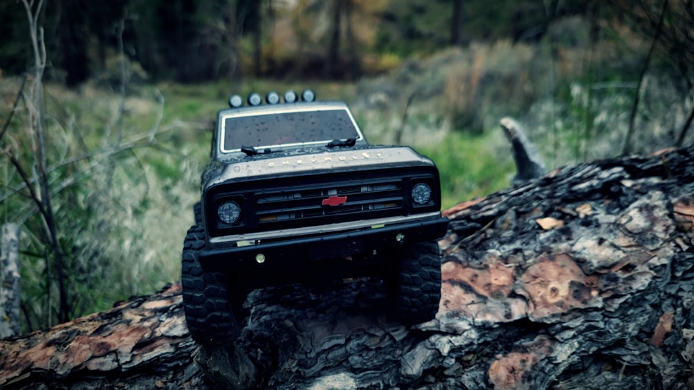 a toy truck on a log in the woods
