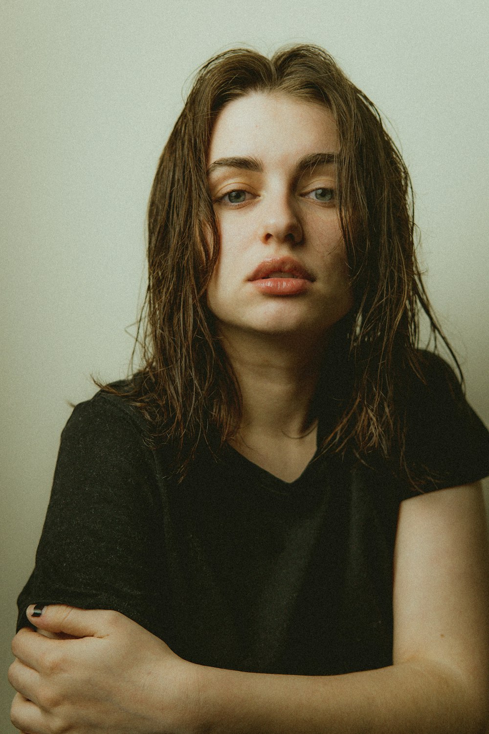 a woman with long hair sitting in front of a white wall