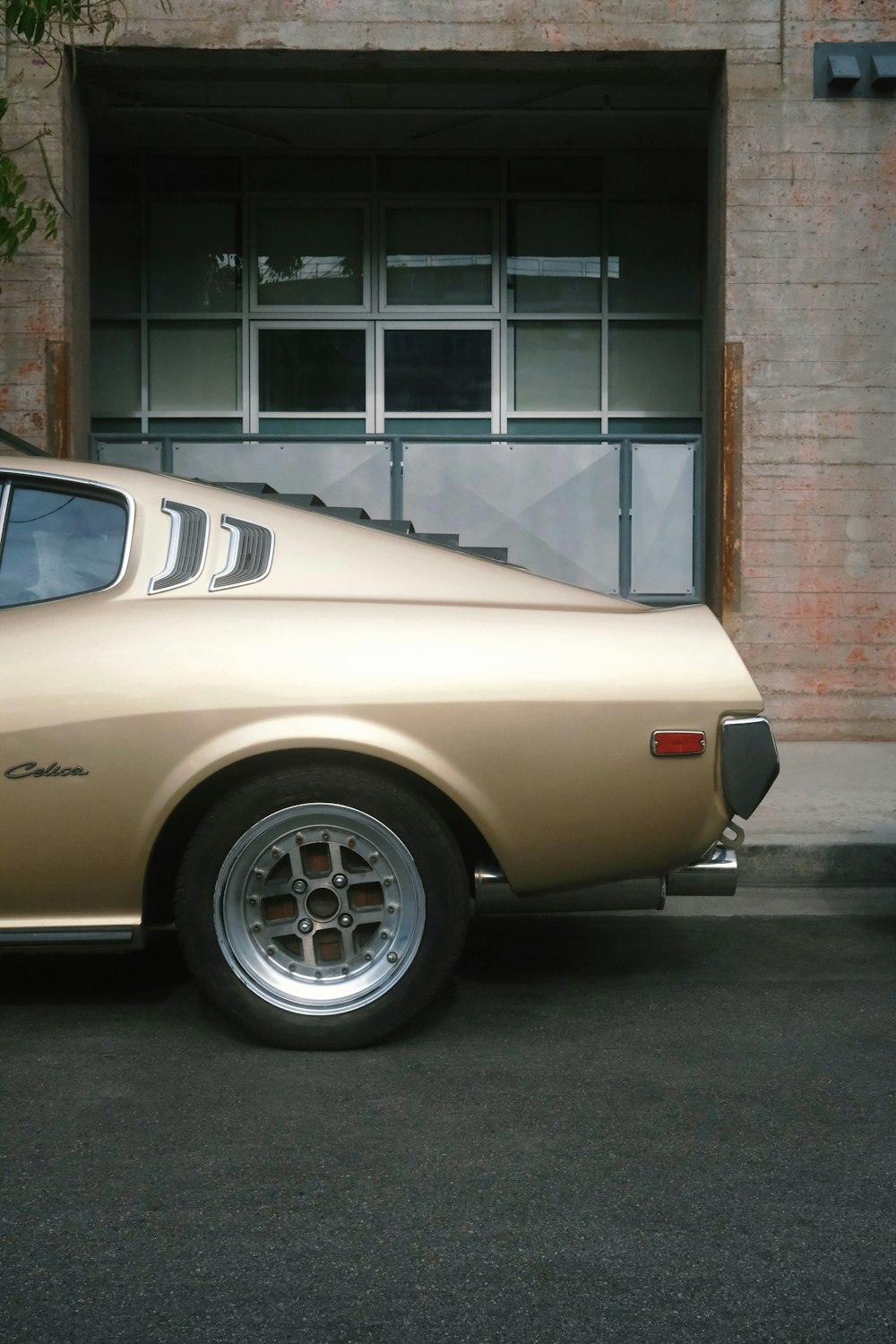 a tan car parked in front of a brick building