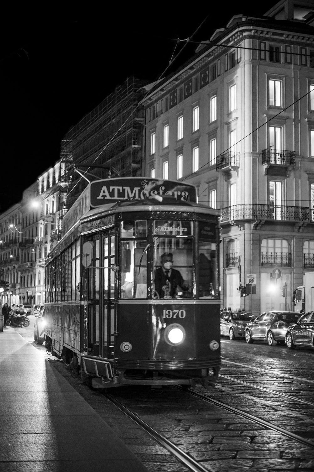 a black and white photo of a trolley on a city street