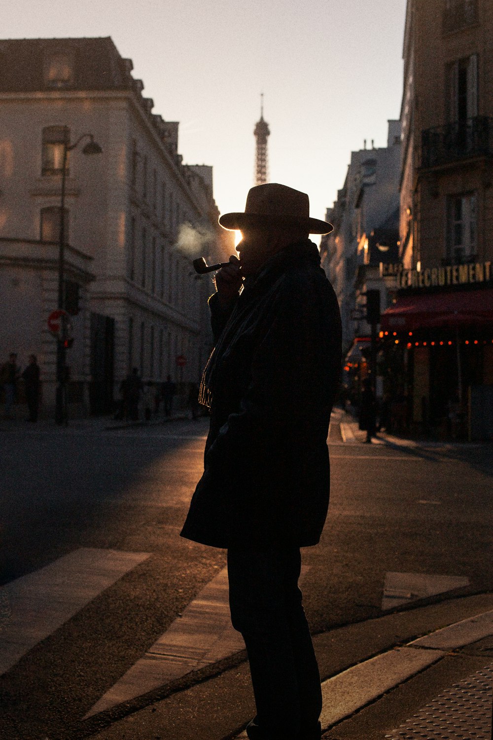 a man standing on the side of a street smoking a cigarette