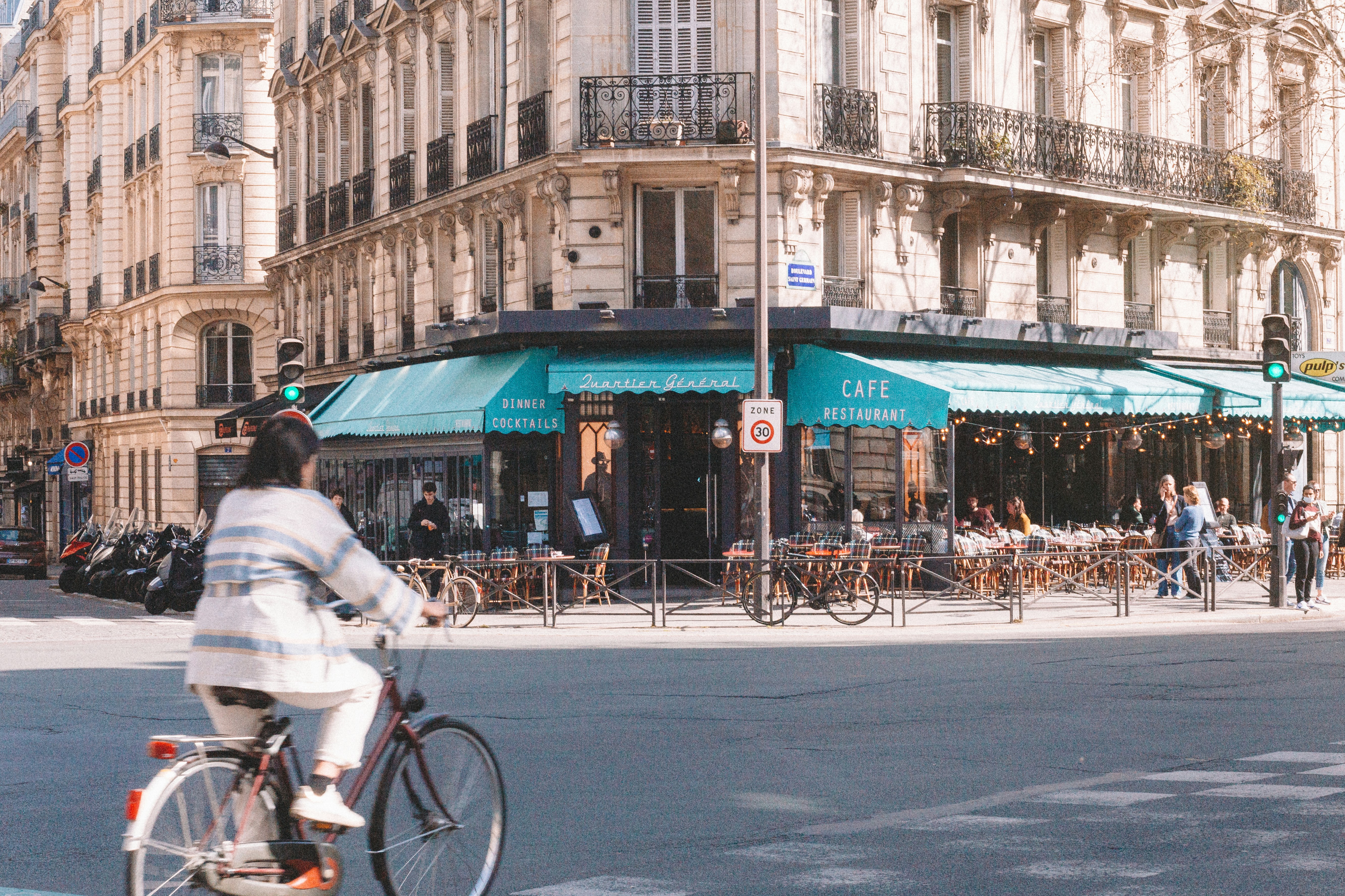 a man riding a bike down a street next to tall buildings, Walking in paris
