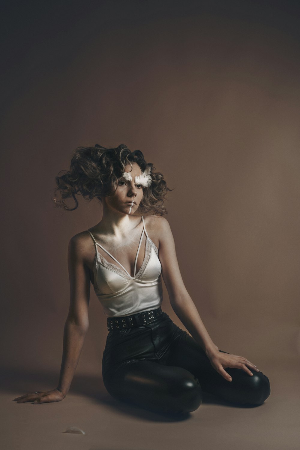 a woman sitting on the ground with her hair blowing in the wind