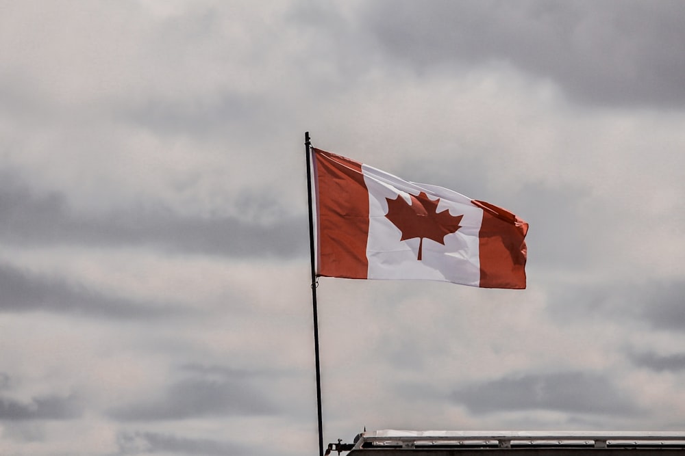 a canadian flag flying in the wind on a cloudy day