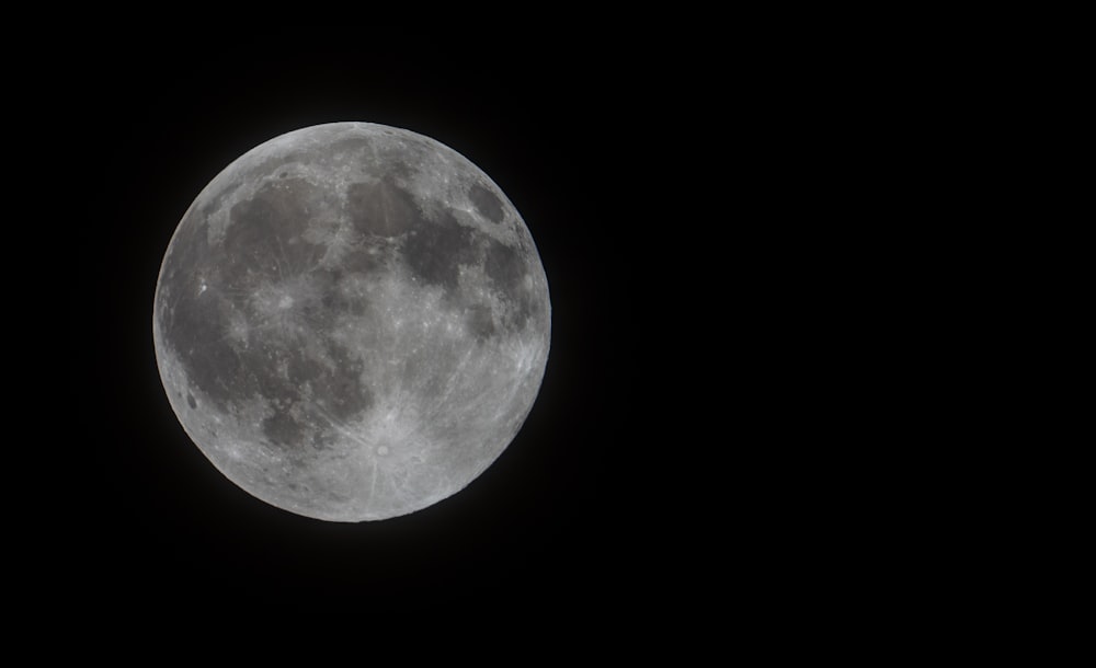 a full moon is seen in the dark sky