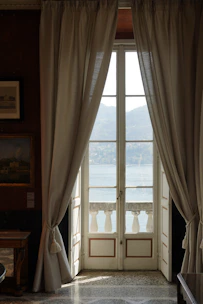 A sunlit, elegant suite with plush furnishings overlooking the Nile River at sunset.