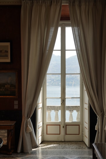 Elegant deluxe suite with warm lighting and a balcony view of Namo Ghat at sunset.