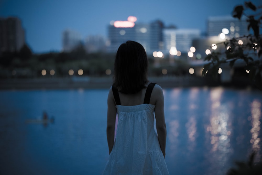 a woman standing in front of a body of water