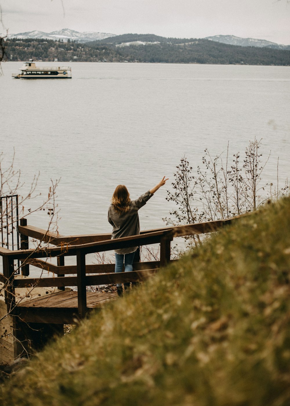 a person standing on a wooden bench near a body of water