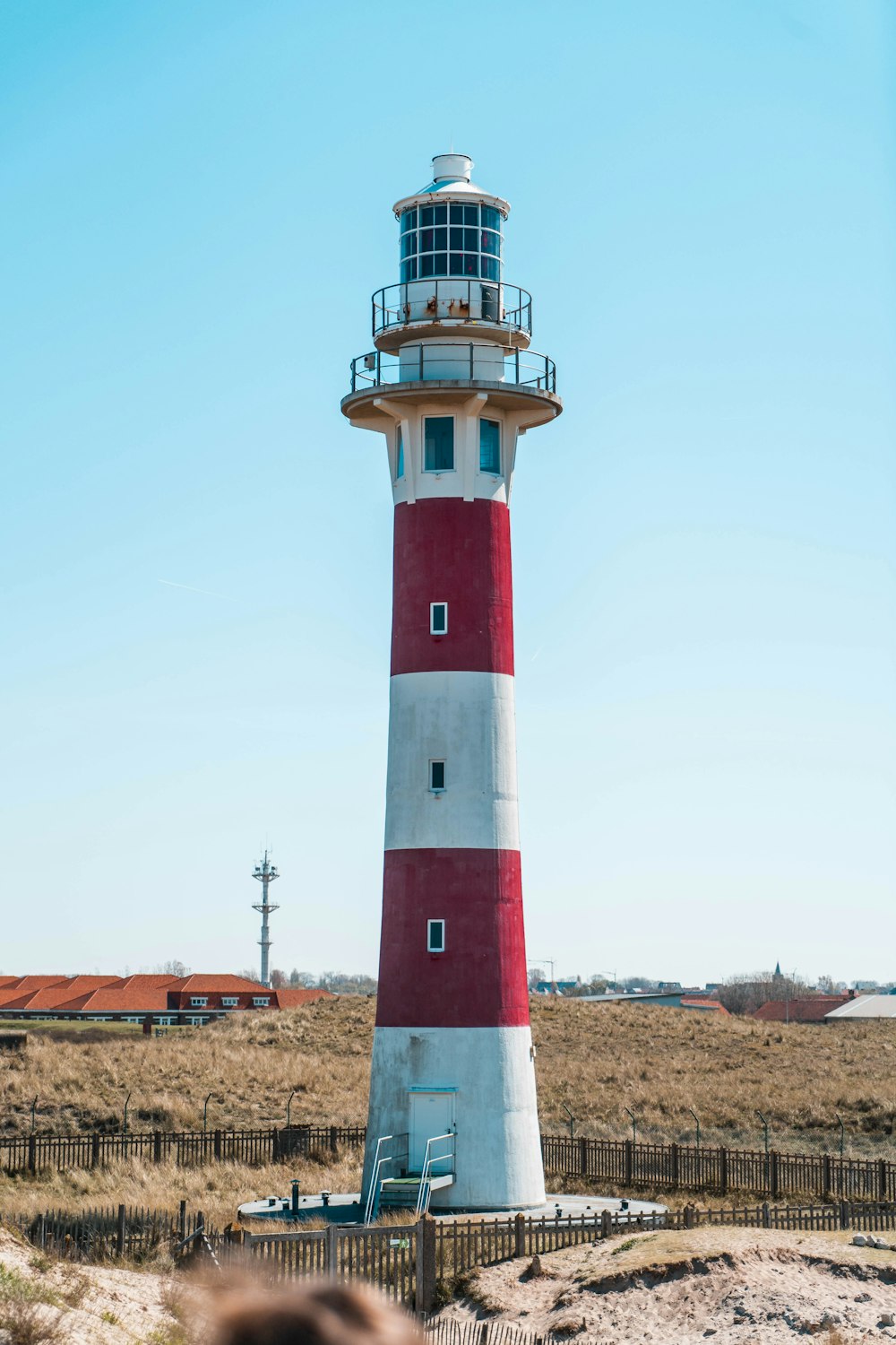 a red and white lighthouse sitting on top of a sandy beach