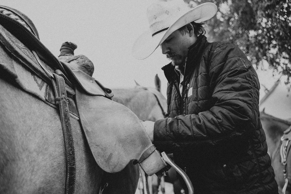 a black and white photo of a man petting a horse