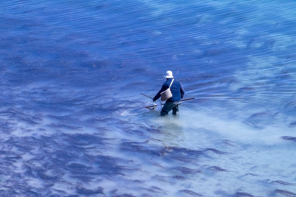 a person in a body of water with a stick