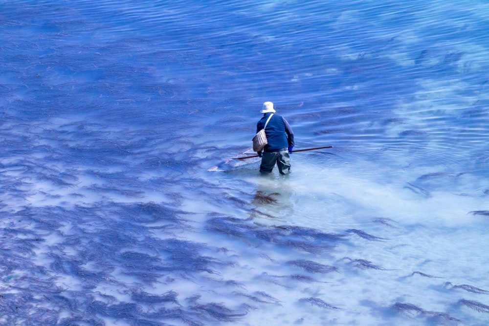 a man standing in a body of water holding a paddle