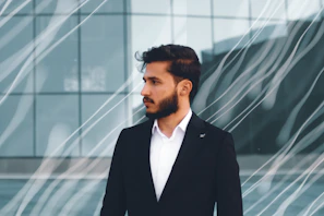Elegant man dressed in black with a modern haircut, standing in a dark room illuminated by soft golden ambient light.