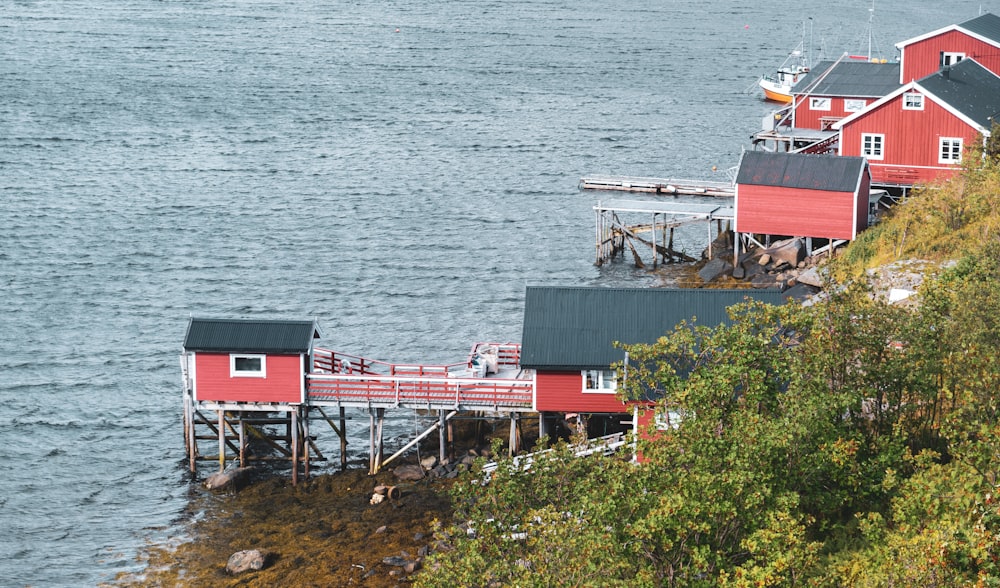 a red house sitting on top of a cliff next to a body of water