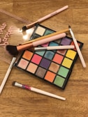 An assortment of colorful makeup palettes and brushes on a vanity.