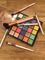 Brightly colored makeup palettes and brushes neatly displayed on a vanity table.
