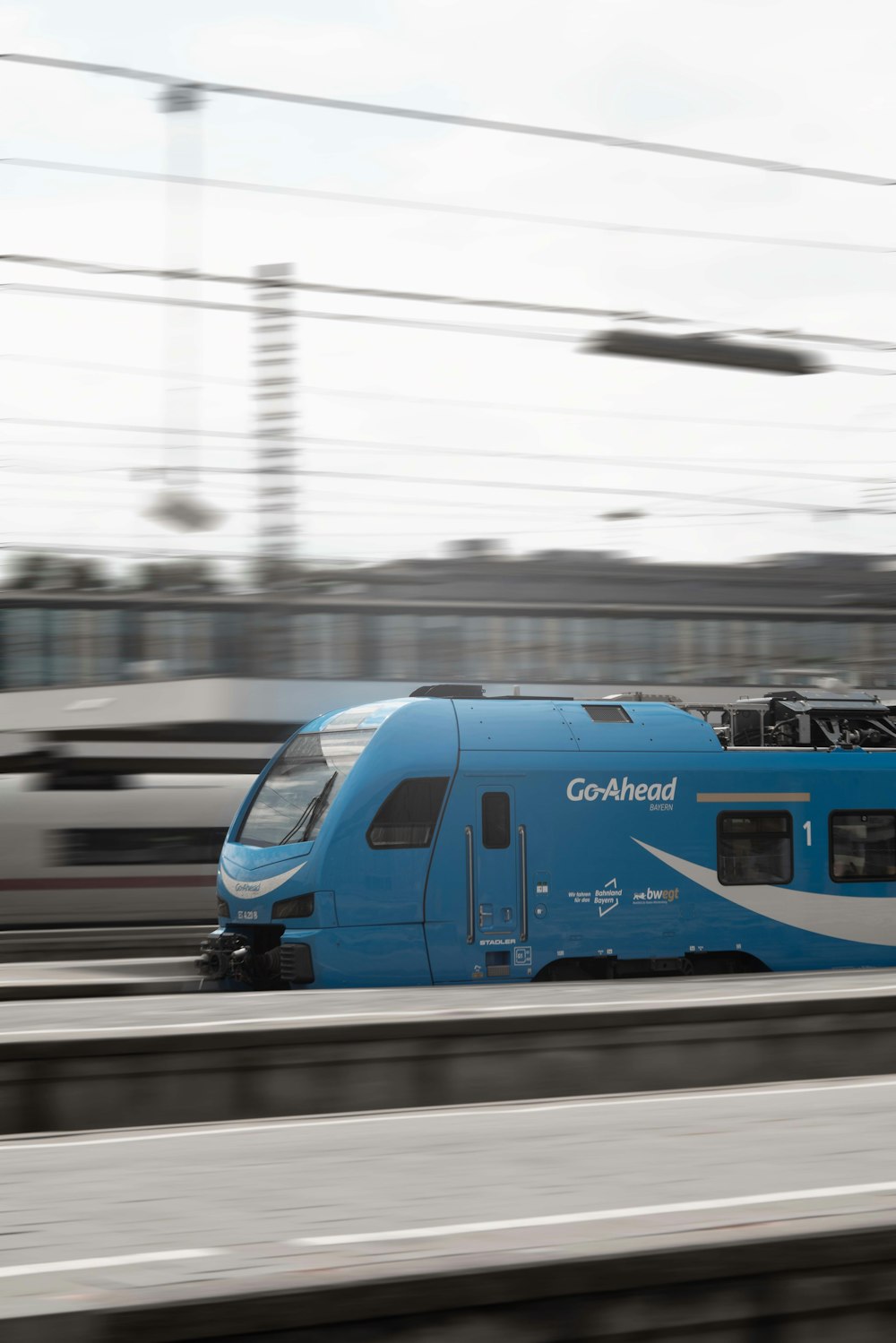 a blue train traveling down train tracks next to a train station