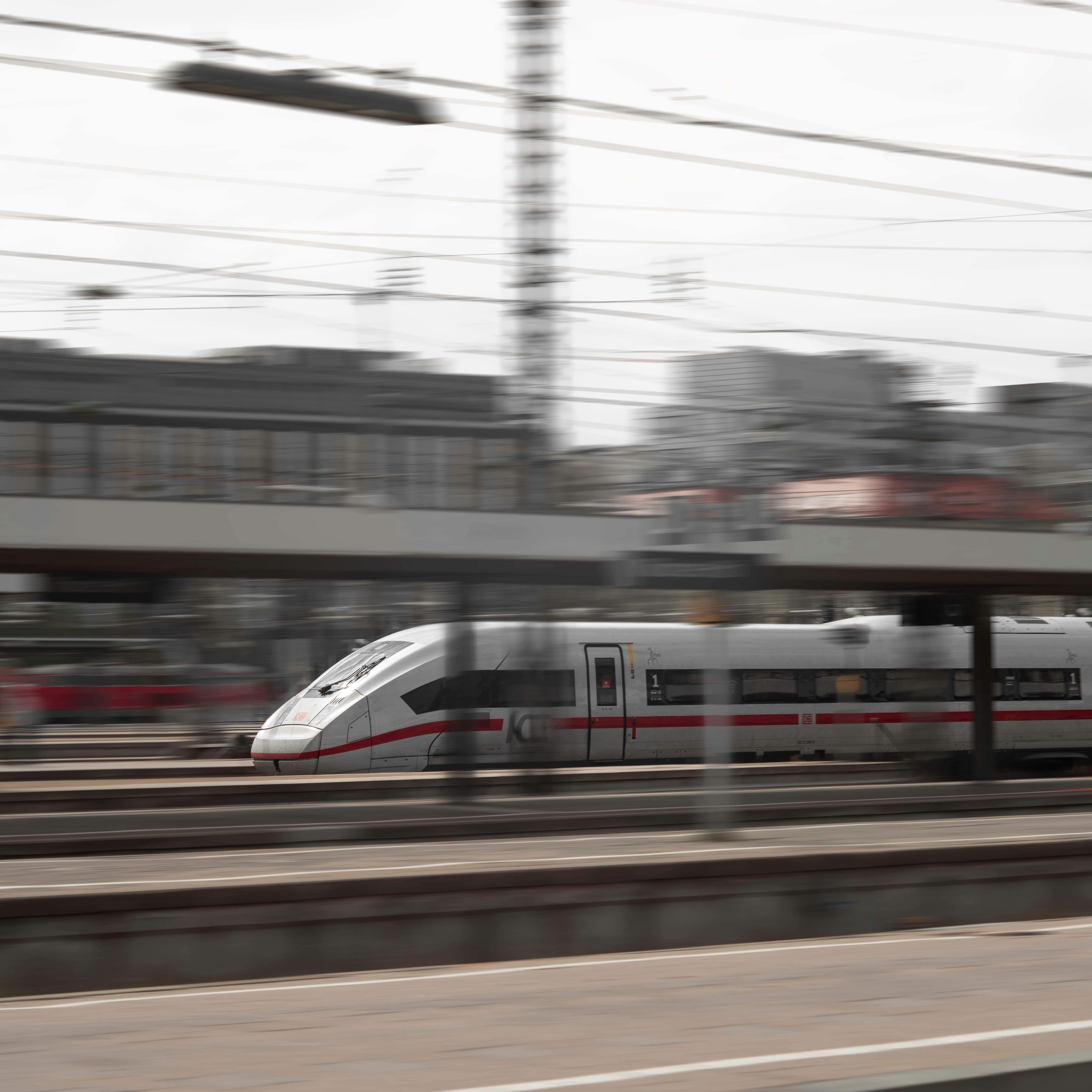 Ein Zug, der neben einer Stadt die Gleise entlang fährt