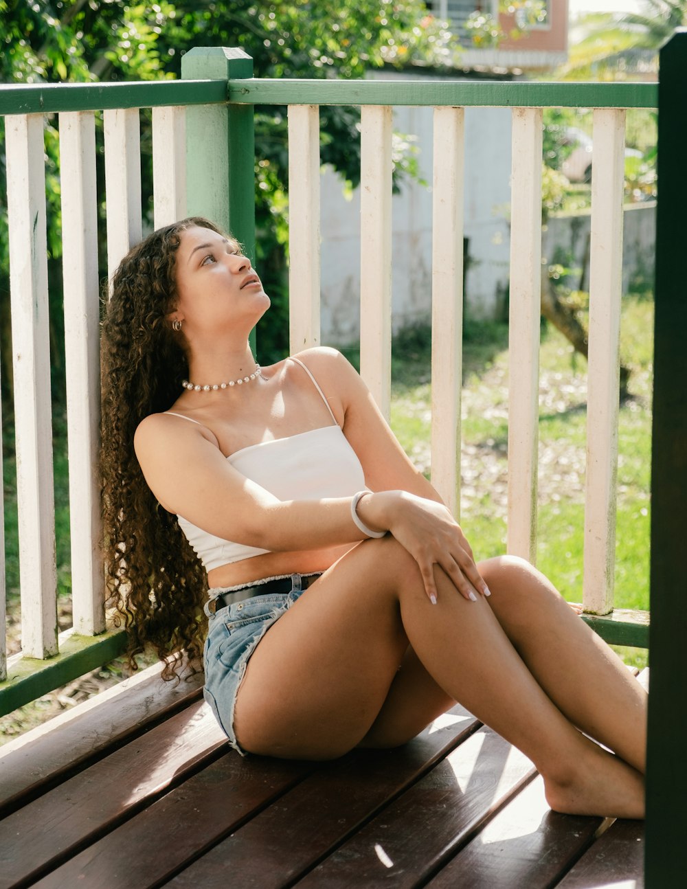 a woman sitting on a wooden deck with her legs crossed