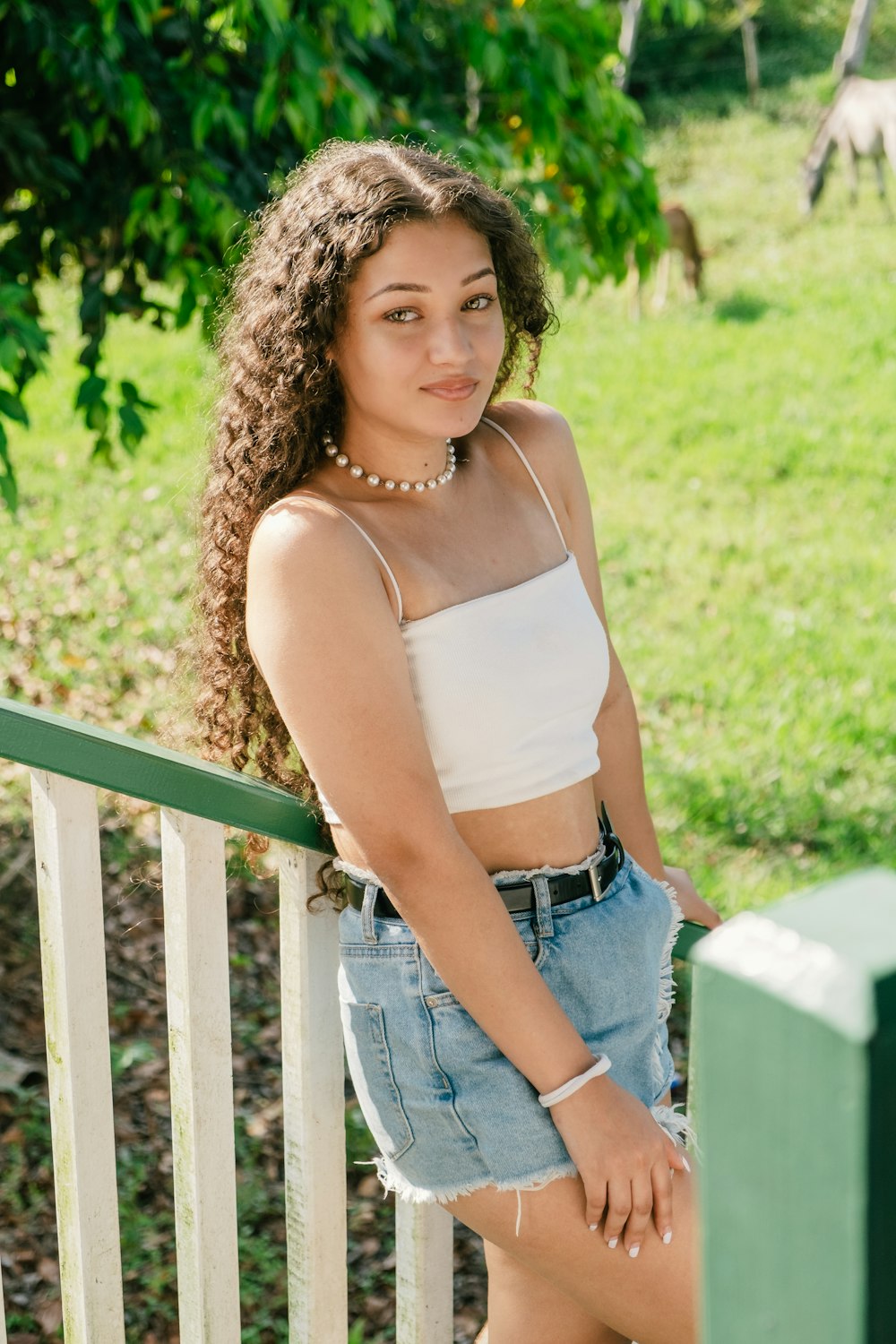 a beautiful young woman standing on a porch next to a fence