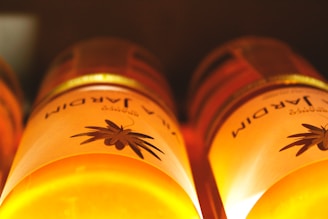 Close-up of golden, cold-pressed organic oil bottles glistening in natural sunlight.